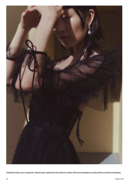 Portrait of an Asian woman in a black tulle dress with tied details, styled with drop earrings, with soft focus and muted lighting.