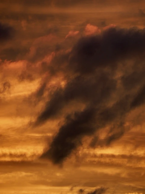 Dramatic cloudscape with dark and light clouds filling the frame, creating a dynamic and textured sky at sunset or sunrise.