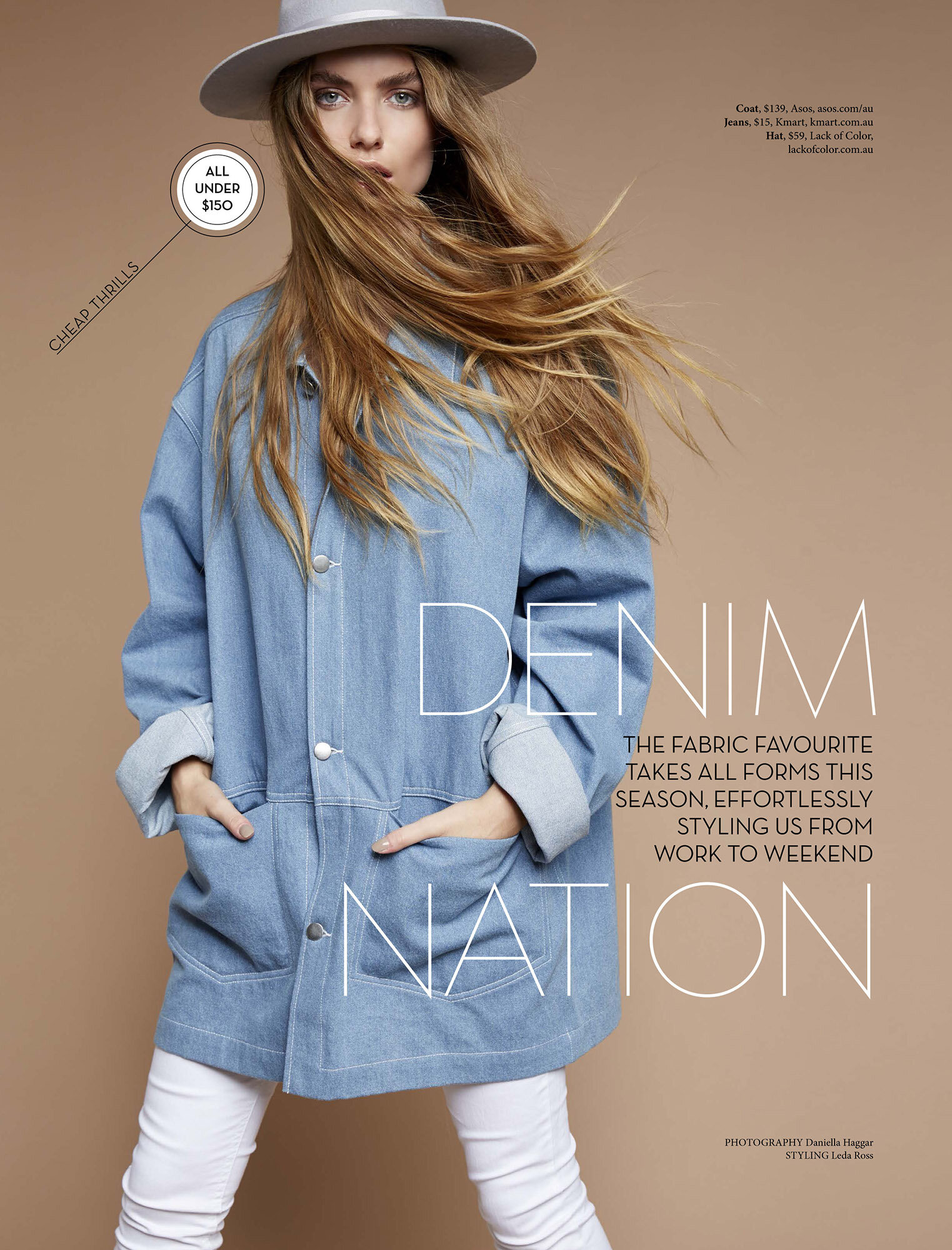 Fashion editorial shot of a woman in a denim jacket, white pants, and a hat against a tan background in a photo studio setting.
