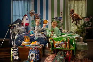 Two children playing in a themed bedroom with space and dinosaur decor, styled by Jerrie Joy Redman Lloyd