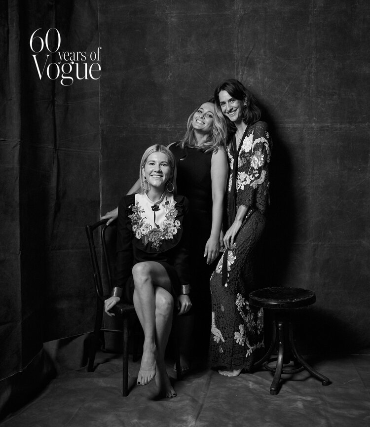 Black and white portrait of three women posing in front of a dark backdrop to celebrate 60 Years of Vogue, featuring formal wear.