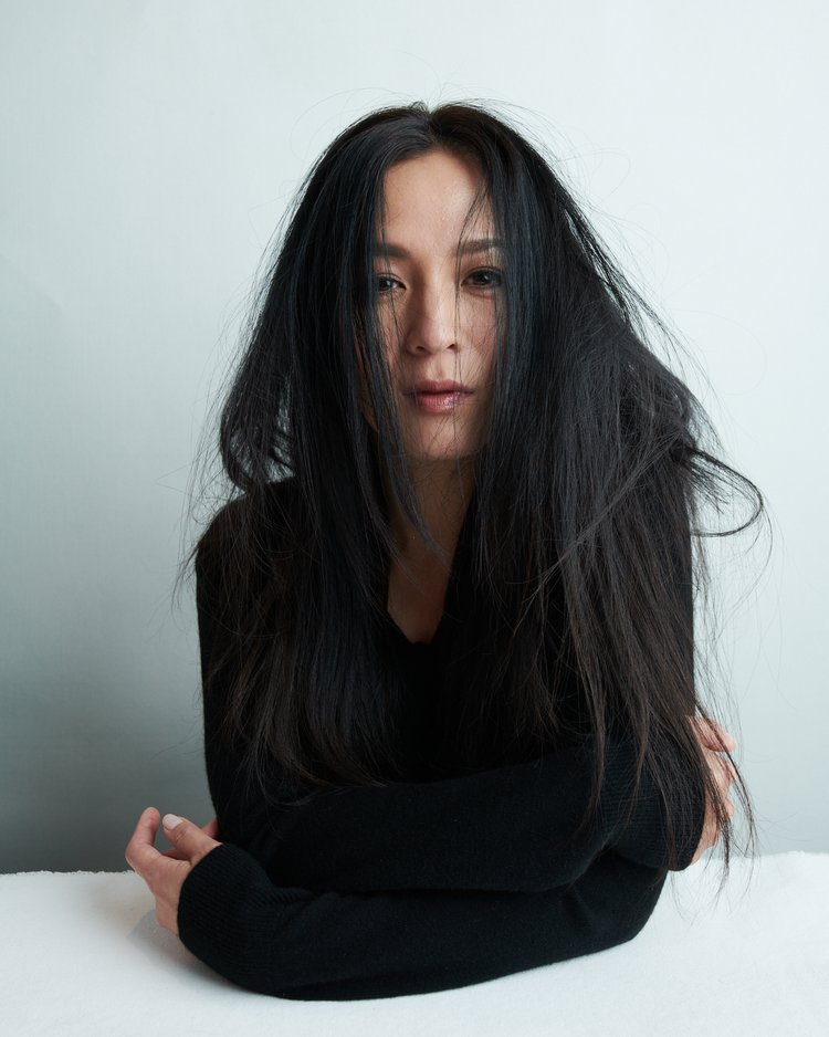 Portrait of an Asian adult female with long black hair wearing a black long sleeve shirt, posing in a white indoor setting.