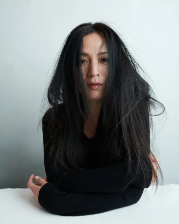 Portrait of an Asian adult female with long black hair wearing a black long sleeve shirt, posing in a white indoor setting.