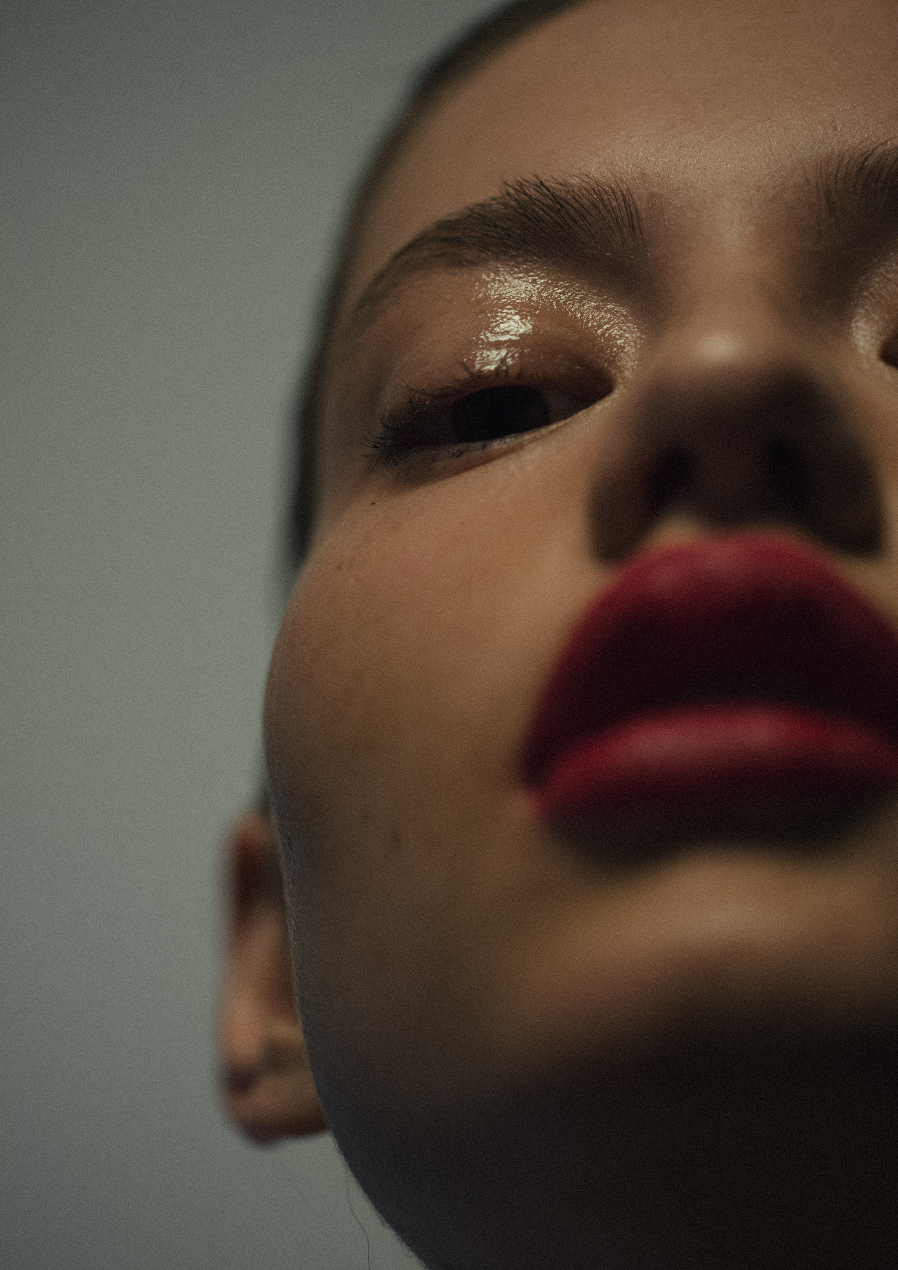 Close-up portrait of a woman with bright red lipstick and fair skin. The frame emphasizes the eye and lip makeup details.