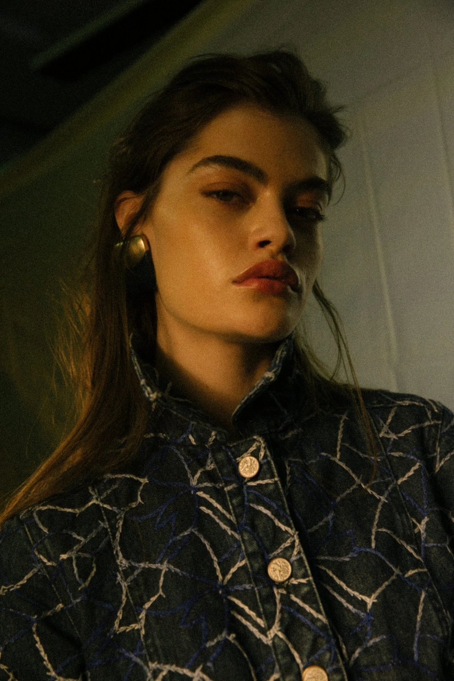 Portrait of a woman wearing a patterned denim jacket and gold earrings shot by photographer Petter Karlstrom.