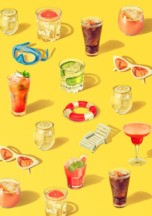 Summer themed flat lay with various cocktails in glasses, along with sunglasses, swimming goggles, a beach chair, and a life preserver.