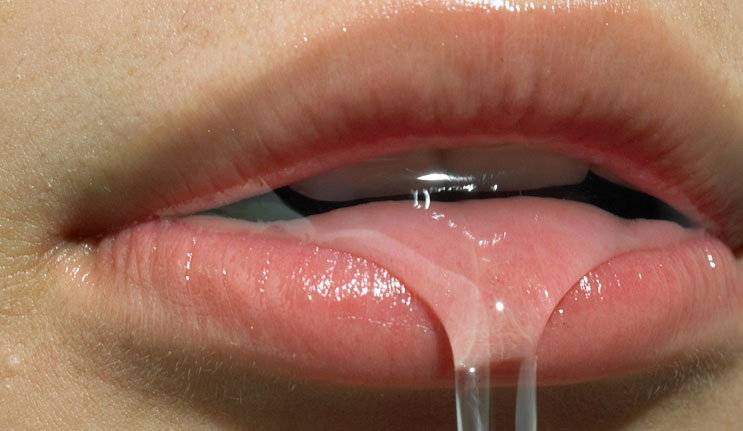 Close-up of human lips and tongue with water dripping from the mouth, highlighting detail and texture in a macro portrait.