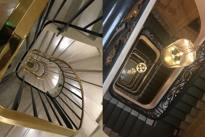 High-angle view down an ornate spiral staircase with brass handrails and hanging pendant lights captured by Jordan Doner.