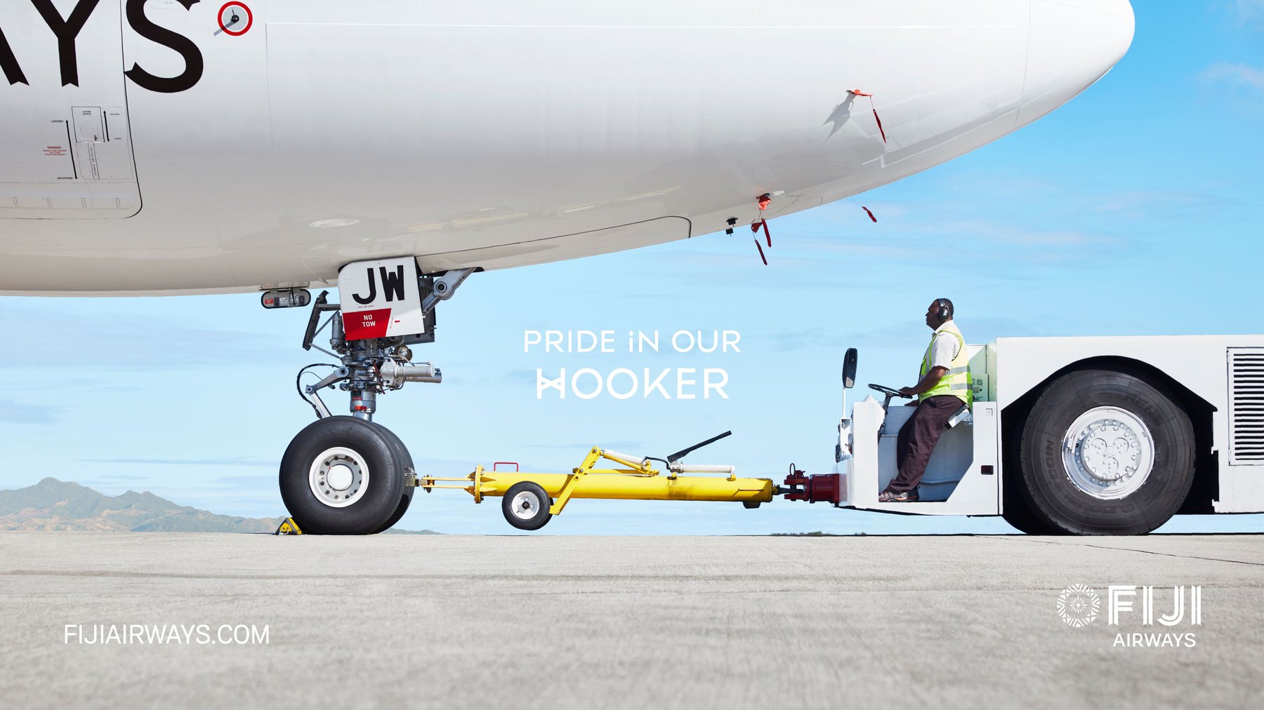 Fiji Airways plane being towed on an airport tarmac with a tow tractor, under a clear sky, showcasing the ground operations.