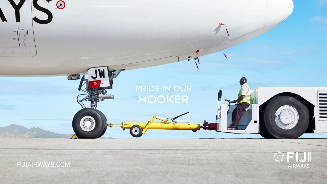 Fiji Airways plane being towed on an airport tarmac with a tow tractor, under a clear sky, showcasing the ground operations.