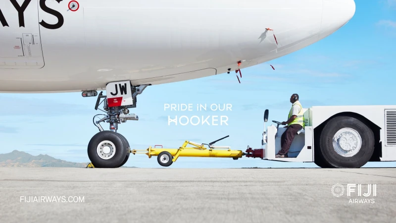 Fiji Airways plane being towed on an airport tarmac with a tow tractor, under a clear sky, showcasing the ground operations.
