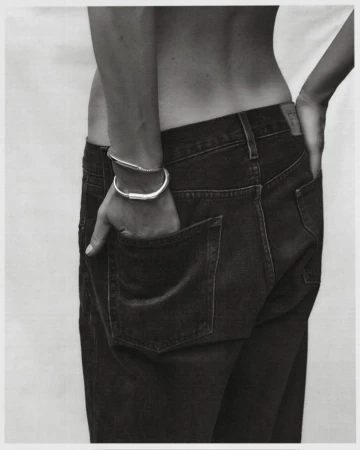 Close-up of a person wearing dark denim jeans and silver bangles, photographed by Darren Mcdonald in Sydney.