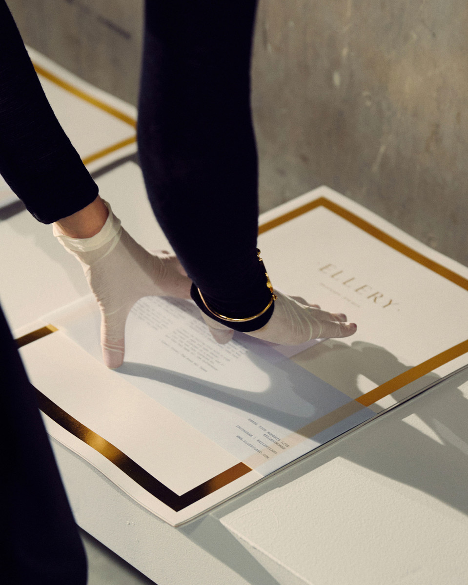 Close-up of gloved hands on marketing brochure, gold accents on white backdrop, readable text and elegant design.