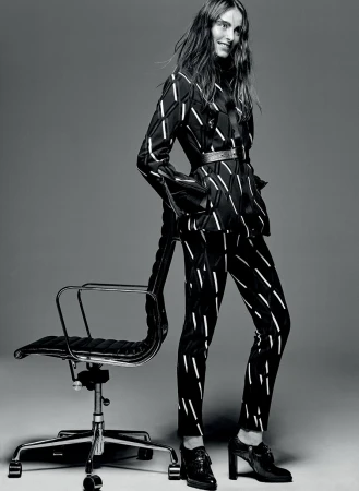 Model standing next to an office chair wearing a patterned matching blazer and trousers styled by Chloe Buttenshaw