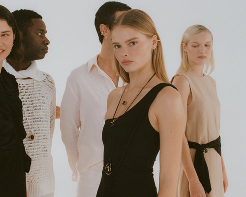 Group of diverse fashion models in a photo studio wearing fashionable apparel and jewelry against a plain white background.