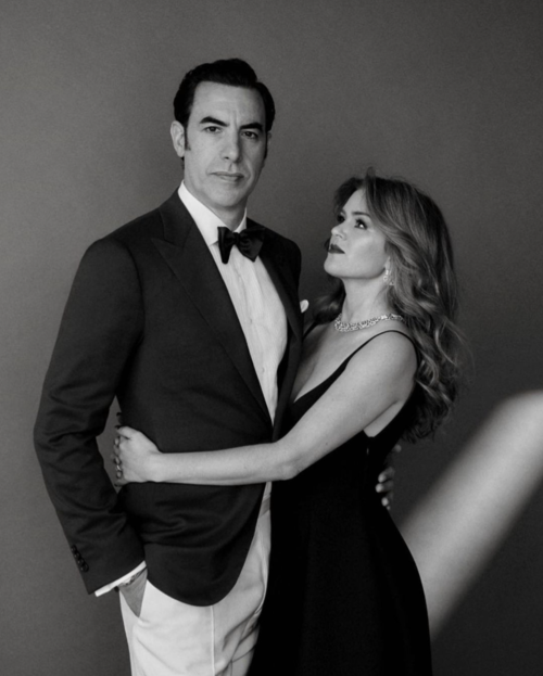 Black and white portrait of a couple in formal wear, the woman with auburn hair looking at the man in a tuxedo with a bow tie.