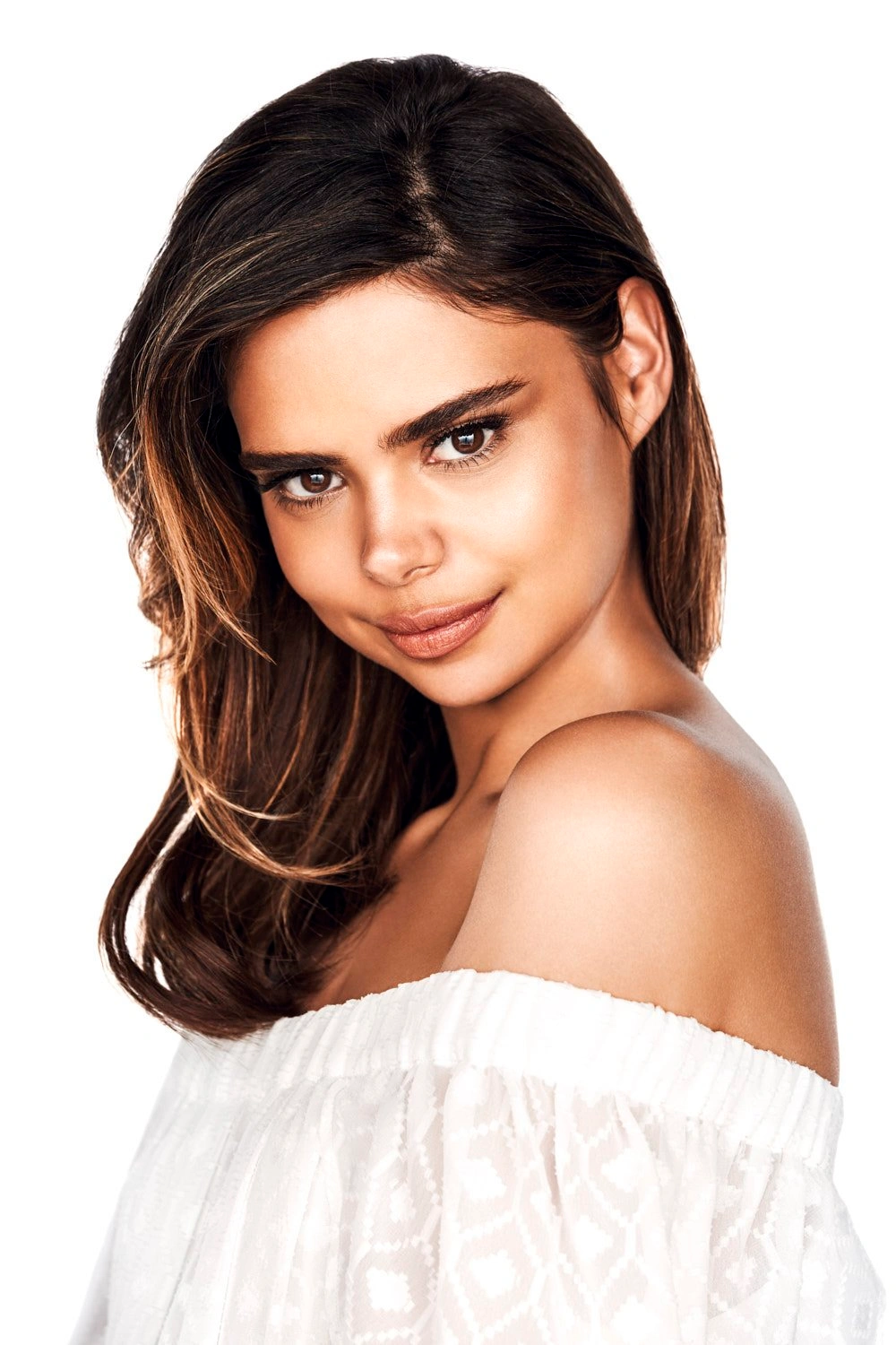 Portrait of a woman wearing an off-the-shoulder white top against a clean white background