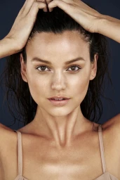 Close-up portrait of a woman with wet hair posing against a dark background, captured by Paul Suesse.