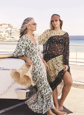 Two women posing outdoors by a classic car in Sydney, styled by Mattie Cronan with floral dresses and a sun visor.