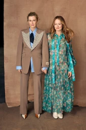 Two women standing side by side against a textured brown backdrop, styled by Mattie Cronan