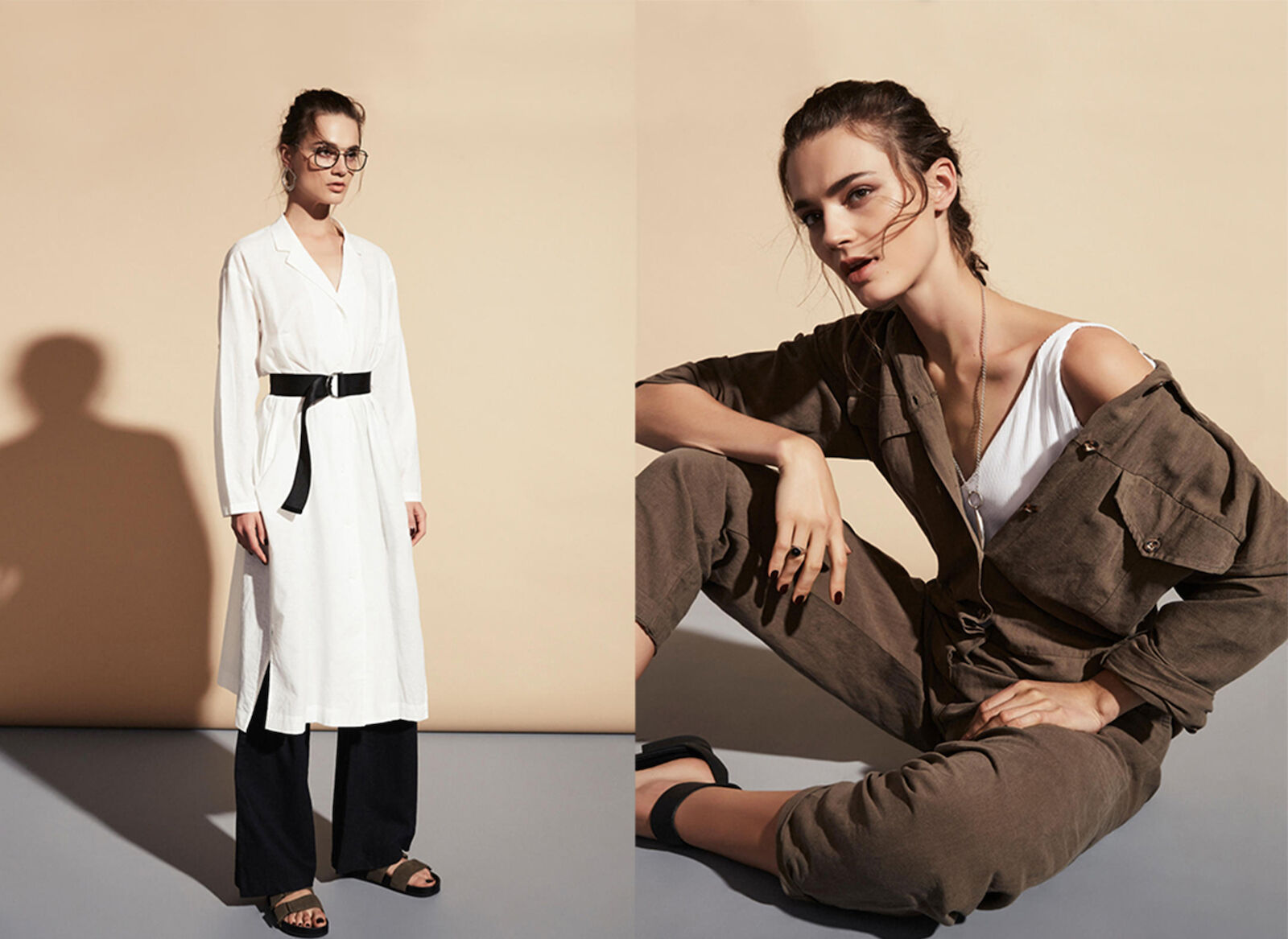 Two fashion models in studio setting, one standing in a white dress with a belt, the other seated in a brown jumpsuit.