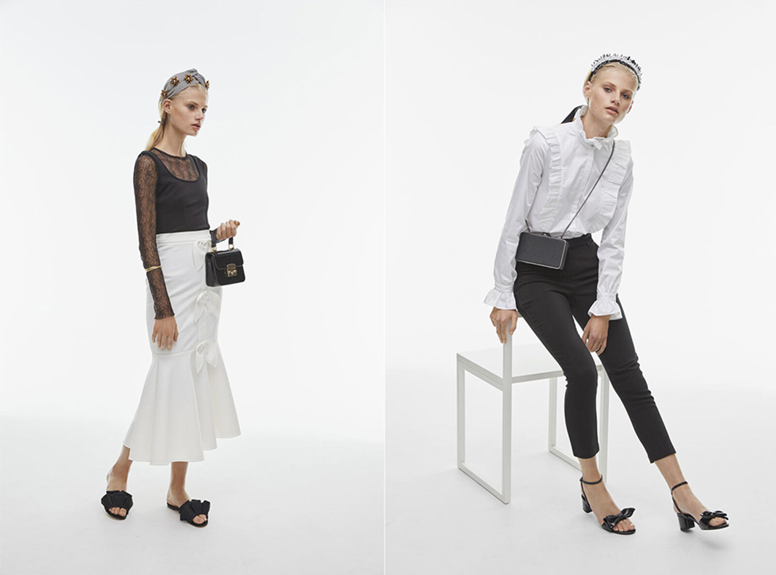 Two fair-skinned women model black and white fashion in a bright photo studio, one sitting on a white cube, both holding small purses.