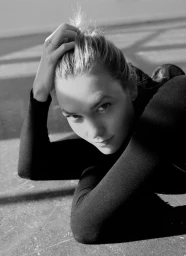 Monochrome portrait of a woman wearing a dark top with her hand in her hair, photographed by Bec Parsons.