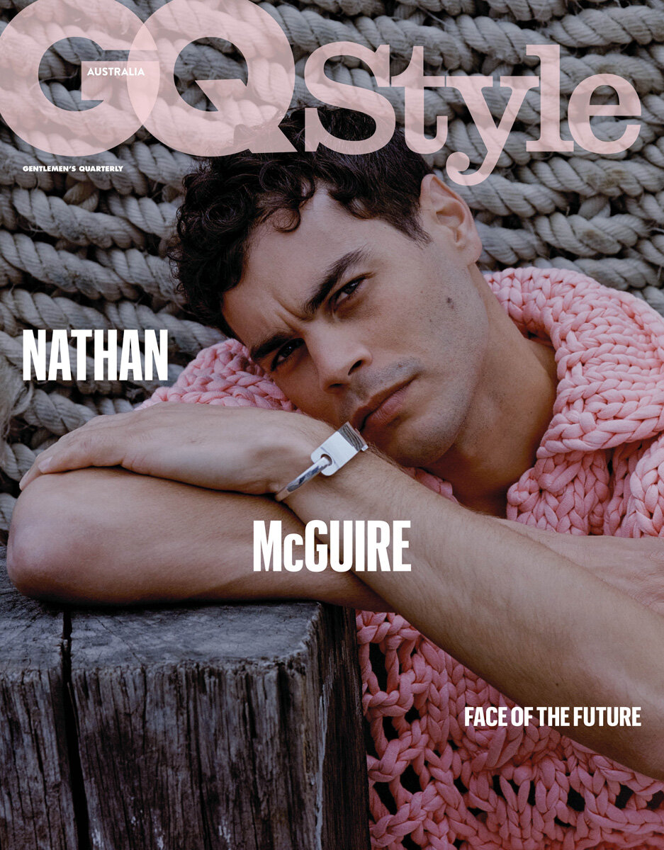 Magazine cover featuring Nathan McGuire, an adult male, wearing a pink knitted sweater, posing against a rope and weathered wood background.
