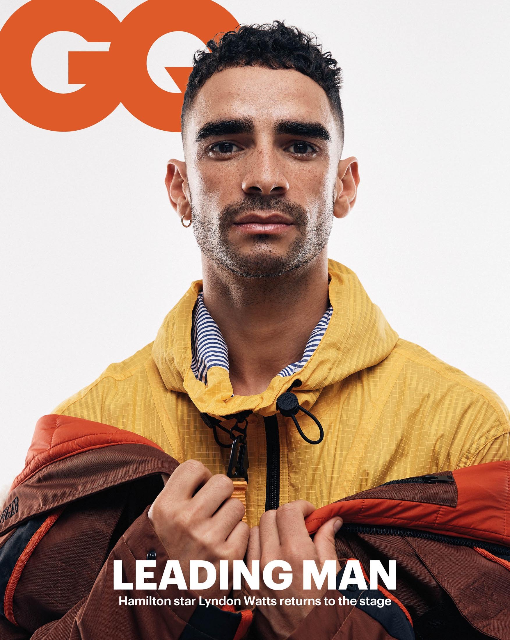 Close-up of Lyndon Watts on magazine cover, wearing yellow and brown jacket. GQ logo in upper left, "Leading Man" text below.