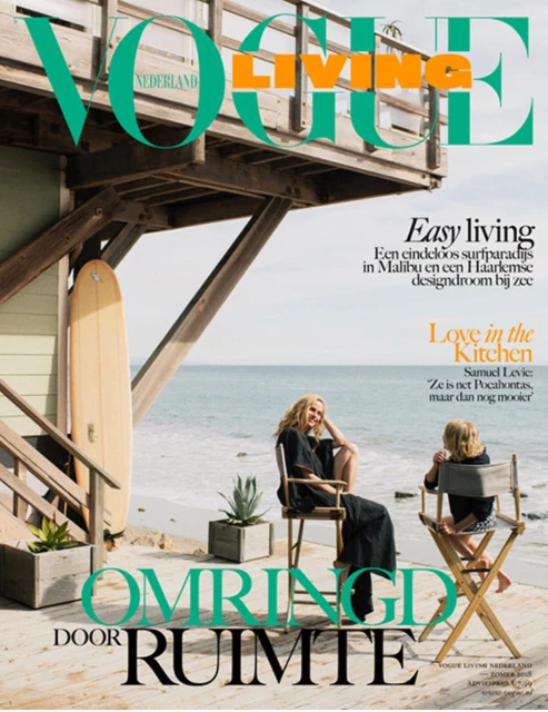 Vogue Living Nederland cover featuring a woman and child sitting in chairs near a beach house, with the ocean in the background.