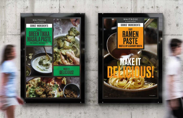 Two Waitrose & Partners Cook's Ingredients posters on a concrete wall, one featuring Green Tikka Masala Paste and the other Ramen Paste.