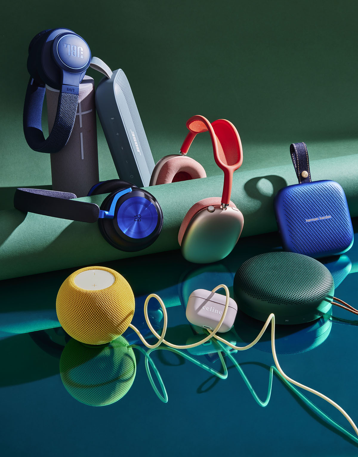 A collection of wireless audio devices including headphones, earbuds, and smart speakers are displayed on a reflective surface.