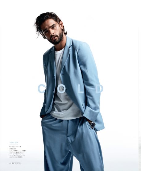 Male model in a light blue suit and white t-shirt posing against a plain white background with overlay text