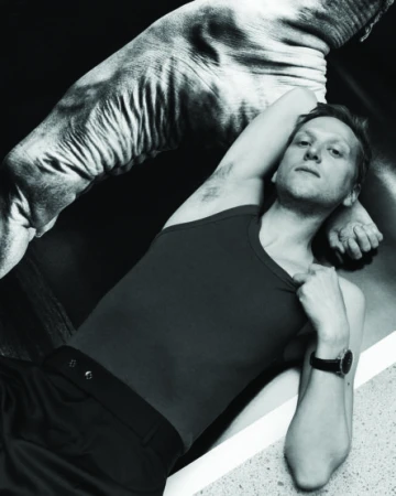 Monochrome portrait of a man in a dark tank top lying down with an arm raised near a patterned surface in Sydney.