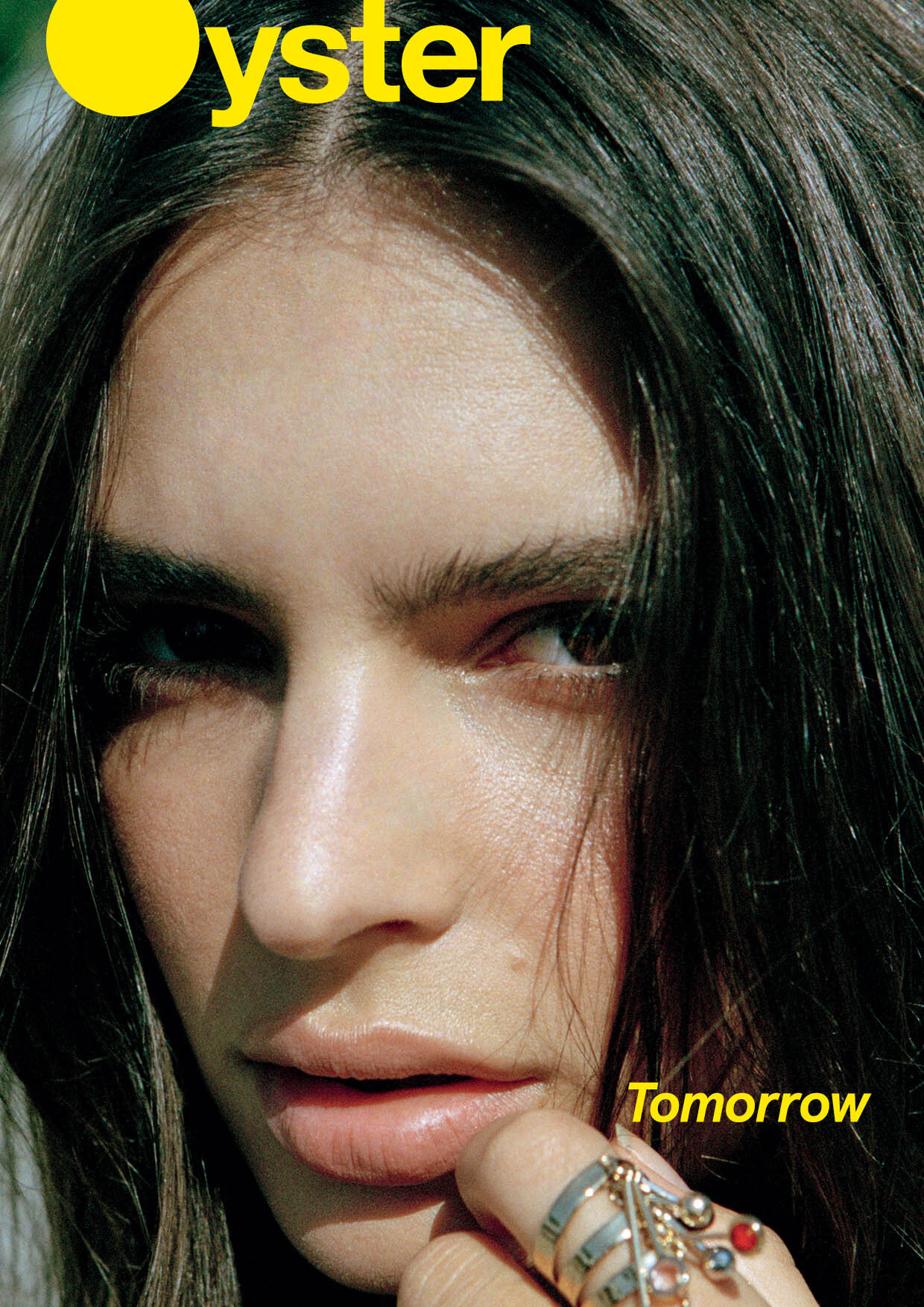 Close-up magazine cover of a woman with brown hair and fair skin, adorned with rings on her finger. Features 'Oyster' and 'Tomorrow' text.