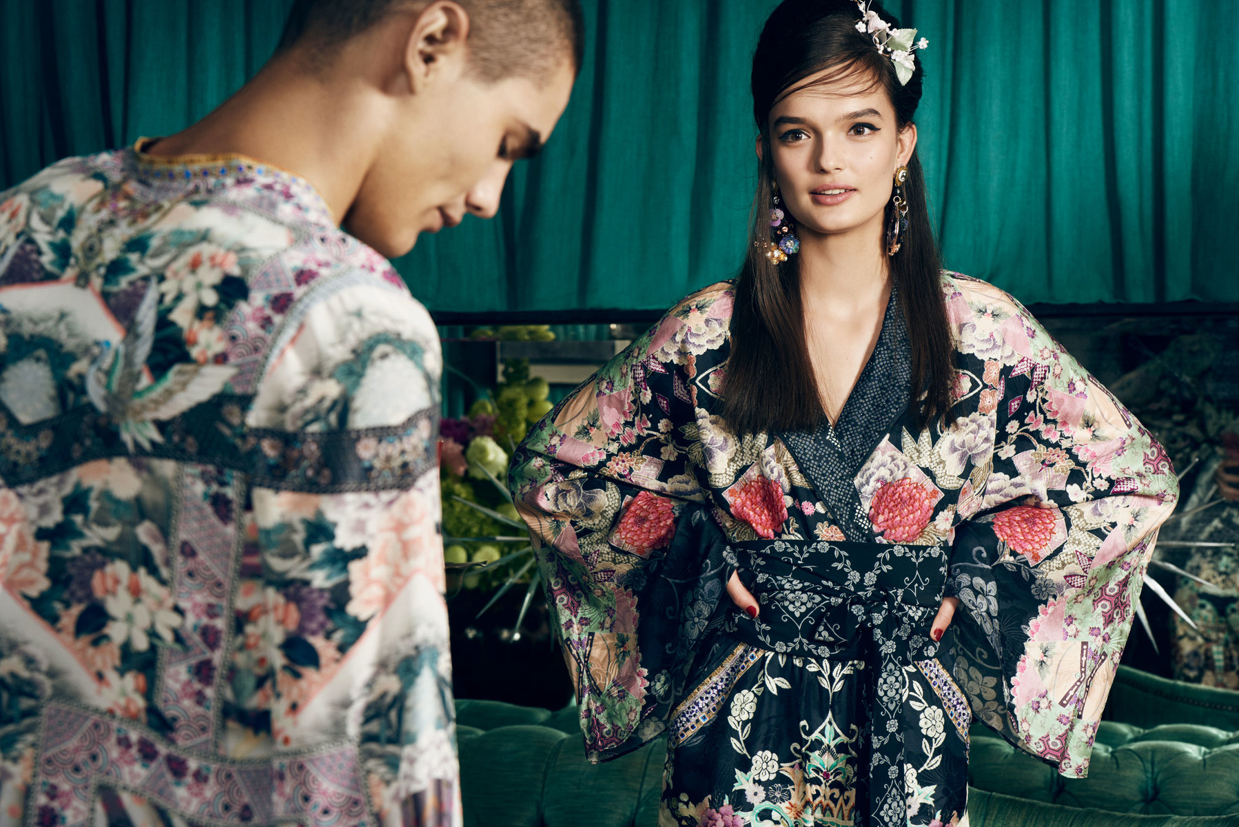 Two fashion models in a photo studio. An adult woman with long hair wears a floral-patterned kimono, and a male model stands beside her.