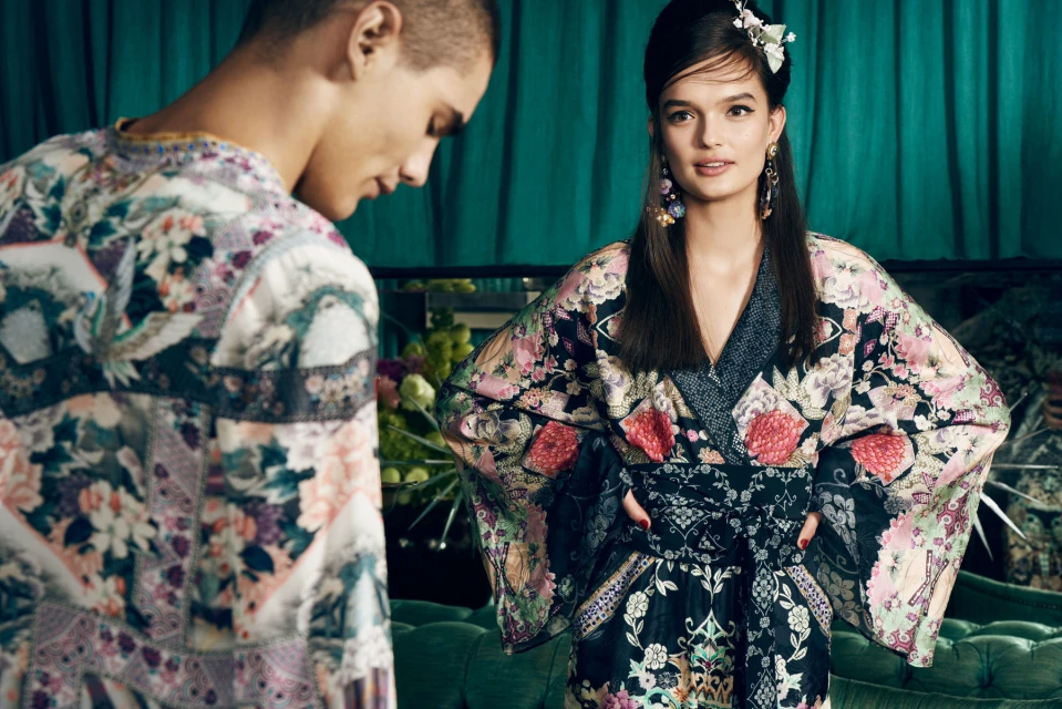 Two fashion models in a photo studio. An adult woman with long hair wears a floral-patterned kimono, and a male model stands beside her.