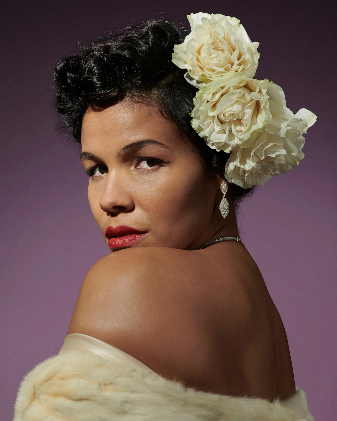 Portrait of a woman with white roses in dark hair wearing a cream stole, shot by Jo Duck