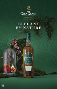 Bottle of The GlenGrant Single Malt Scotch Whisky in a studio setting with decorative greenery and elegant product presentation.
