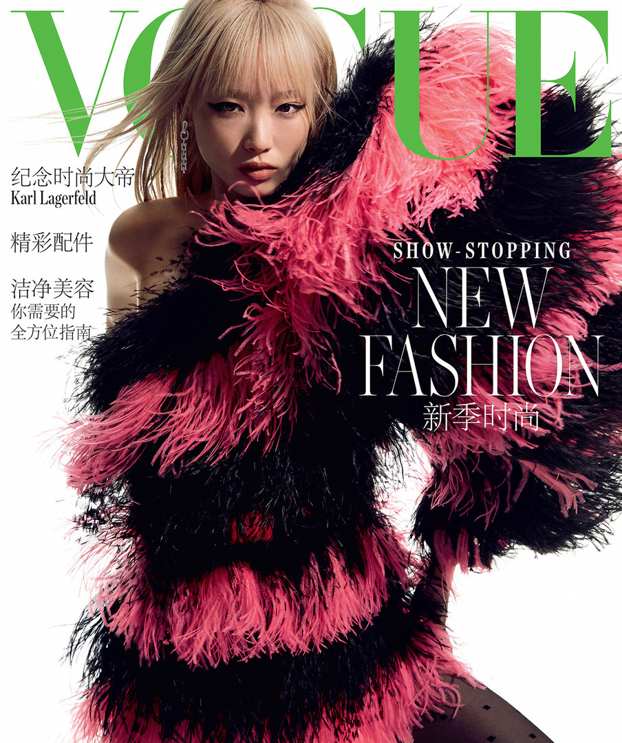 Vogue magazine cover featuring a woman with blonde hair in a black and pink feather dress against a white background.