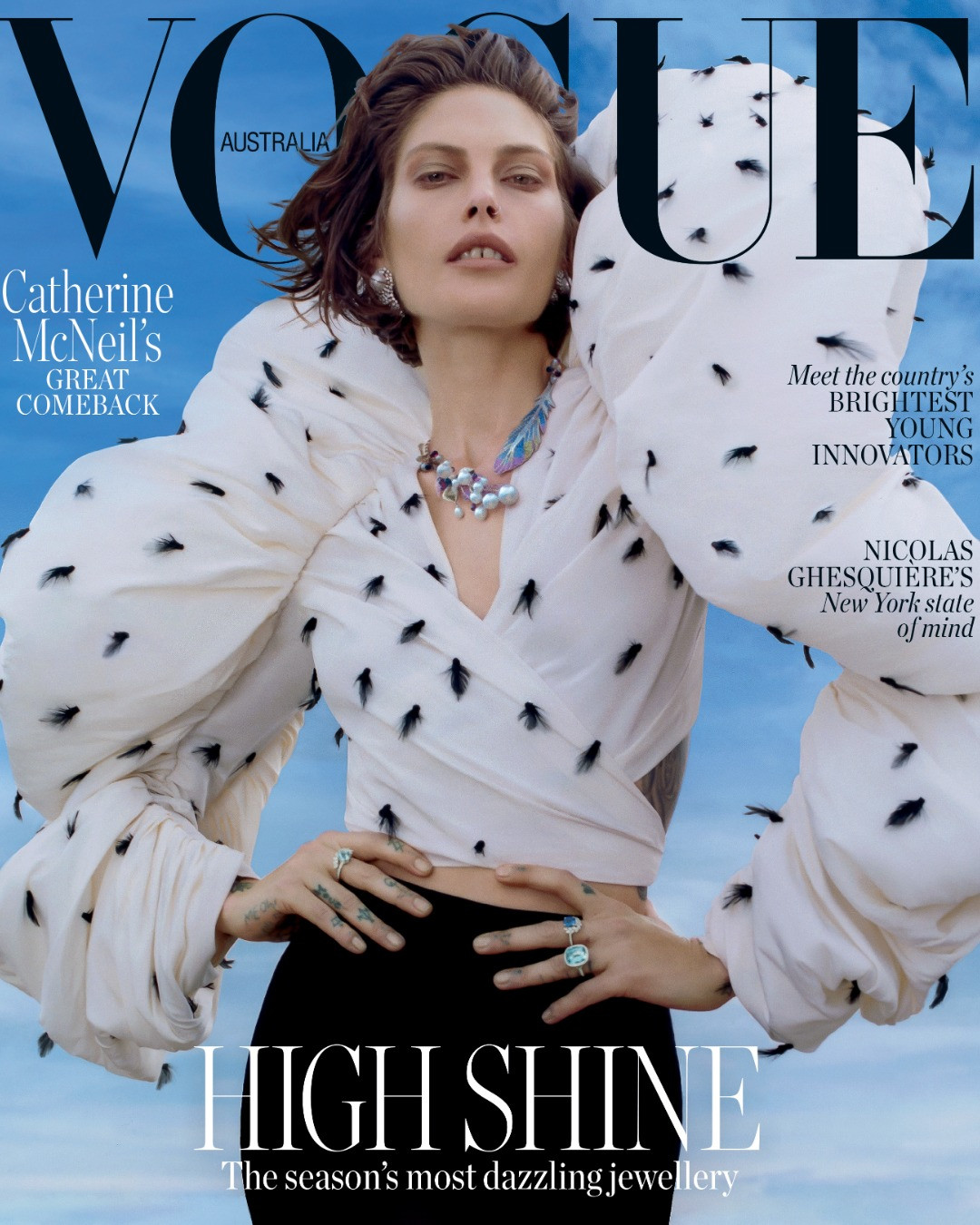 Vogue Australia cover featuring model Catherine McNeil in a white, patterned, voluminous top with pearl jewellery against a blue sky backdrop.
