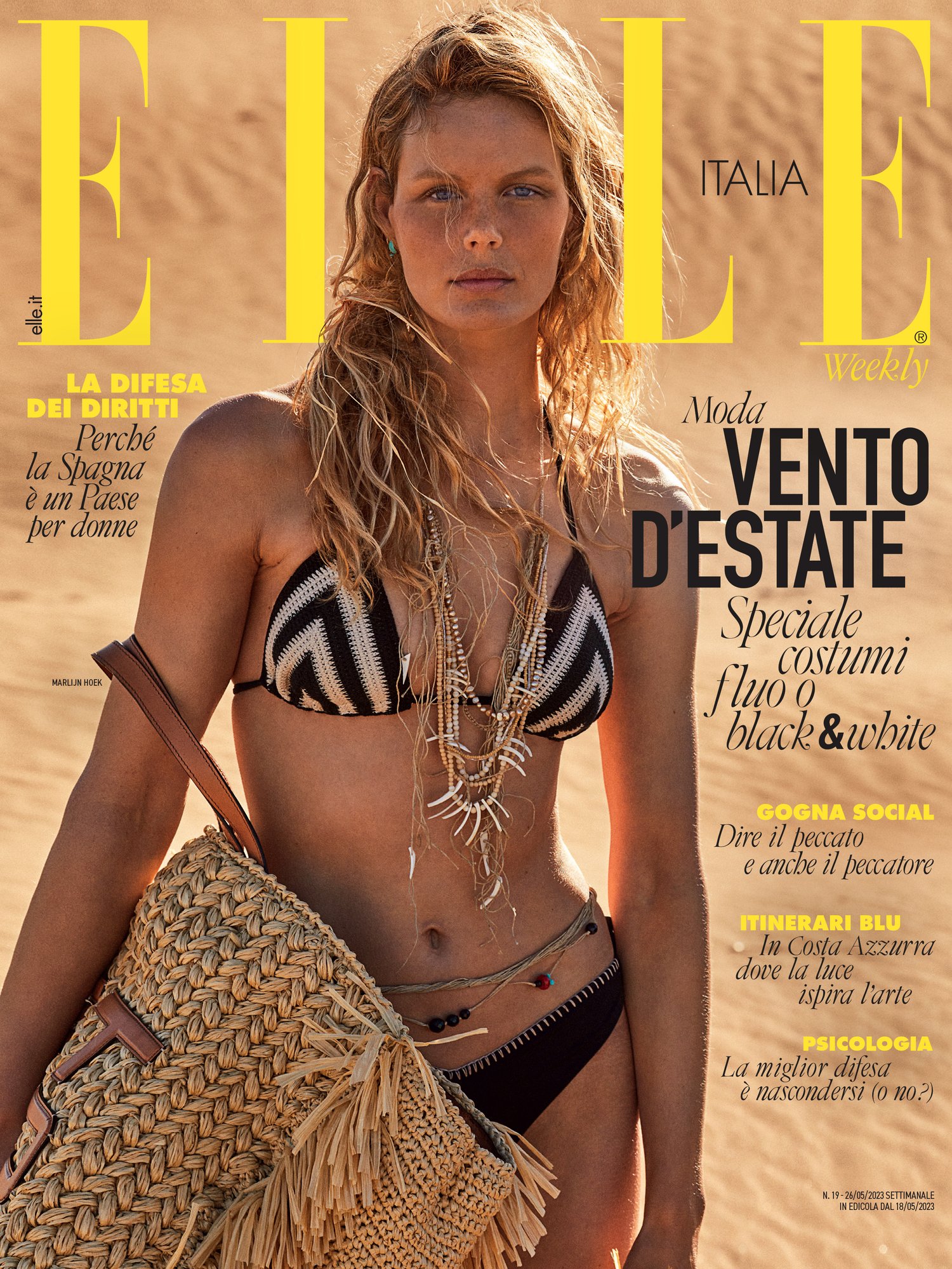 Elle Italia magazine cover featuring a blond woman in a bikini with a straw bag on a sand dune background, fashion and summer concept.