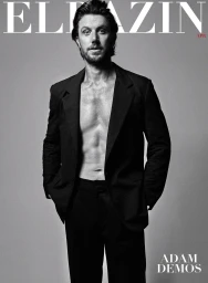 Portrait of actor Adam Demos wearing an open dark suit jacket against a grey background photographed by Simon Upton