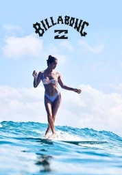 Woman in floral patterned bikini surfing on an ocean wave under a clear sky with Billabong logo above.