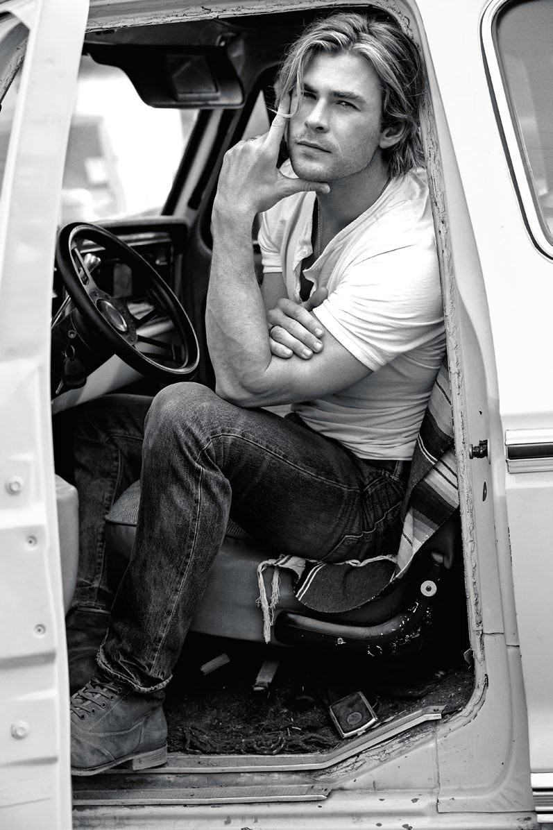 Black and white portrait of a light-skinned adult male sitting in the driver's seat of an old truck, leaning his arm on the door.