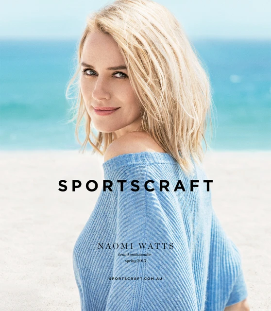 Blonde woman smiles in a light blue sweater in a fashion campaign image. Light blue ocean and sky in the background. Soft light.