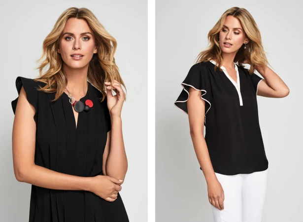 Blonde female model wearing a black short-sleeve top against a light grey studio background.