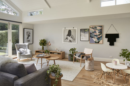 Bright, airy living room featuring neutral decor, modern furniture, and natural light streaming through large windows. Artwork adorns the walls.