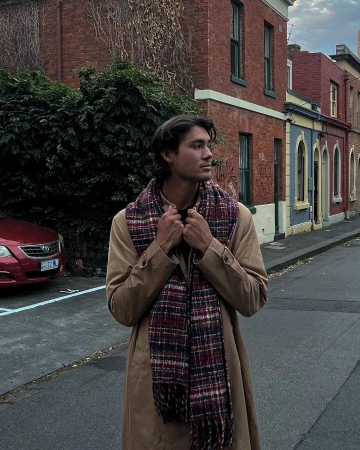 Man wearing a camel trench coat and plaid scarf standing on an urban street in Sydney by Andy Davie