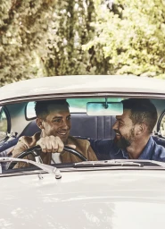 Two men smiling while sitting inside a classic white car, photographed by Anson Smart in Sydney.